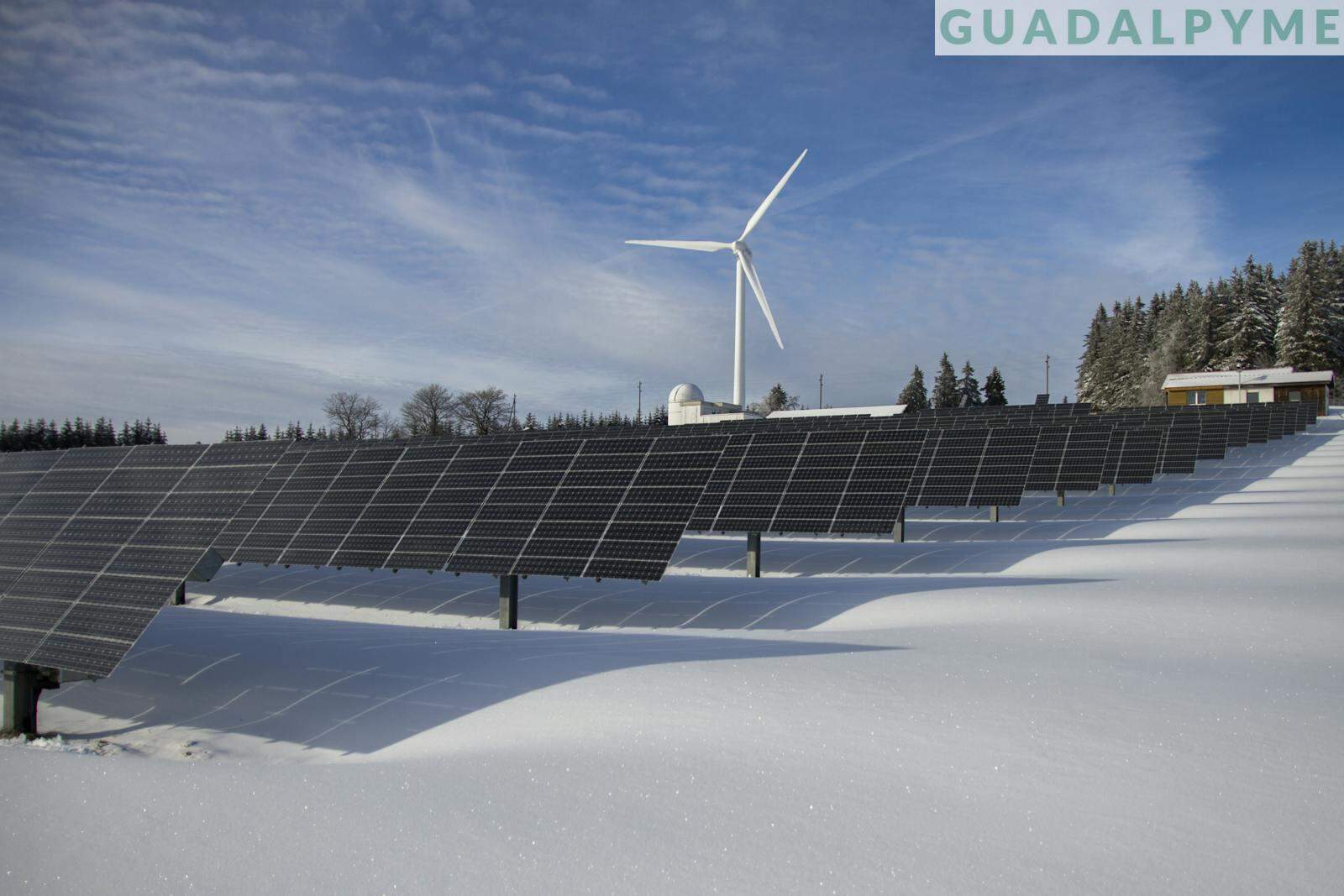 Solar Panels on Snow With Windmill Under Clear Day Sky